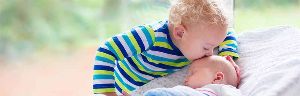 child kissing baby's forehead